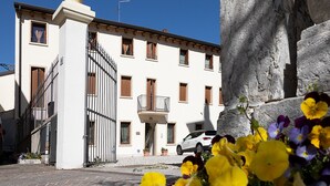 Un edificio blanco con un balcón y un coche estacionado adelante.