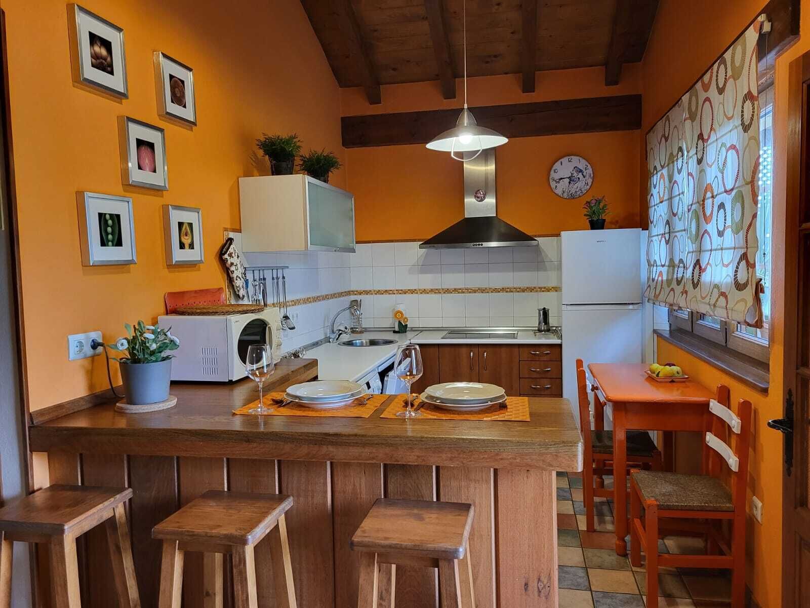 Une cuisine avec un îlot central en bois, des tabourets de bar, un évier et une horloge au mur.