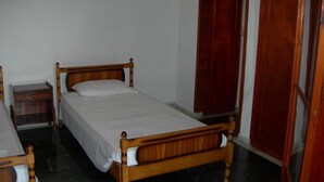 A single bed with a wooden frame and white bedding in a room with a dark marble floor. - APARTMENT FOR 6 PERSONS AT THE CENTER OF BARBATI, 50 METERS FROM THE BEACH (Corfu)