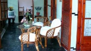 A room with a round table, wicker chairs, a potted plant, and a wooden door. - APARTMENT FOR 6 PERSONS AT THE CENTER OF BARBATI, 50 METERS FROM THE BEACH (Corfu)