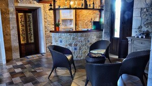A stone-walled bar area with wicker chairs, a potted plant, and a window. - Carizza Country Luxury Villa (Rosolini)