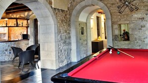 A pool table with a red felt surface, surrounded by stone walls and arches. - Carizza Country Luxury Villa (Rosolini)