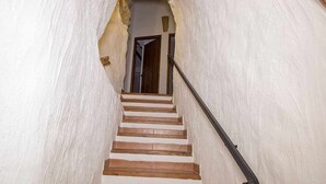 A staircase with wooden steps and a black handrail, leading to a doorway.