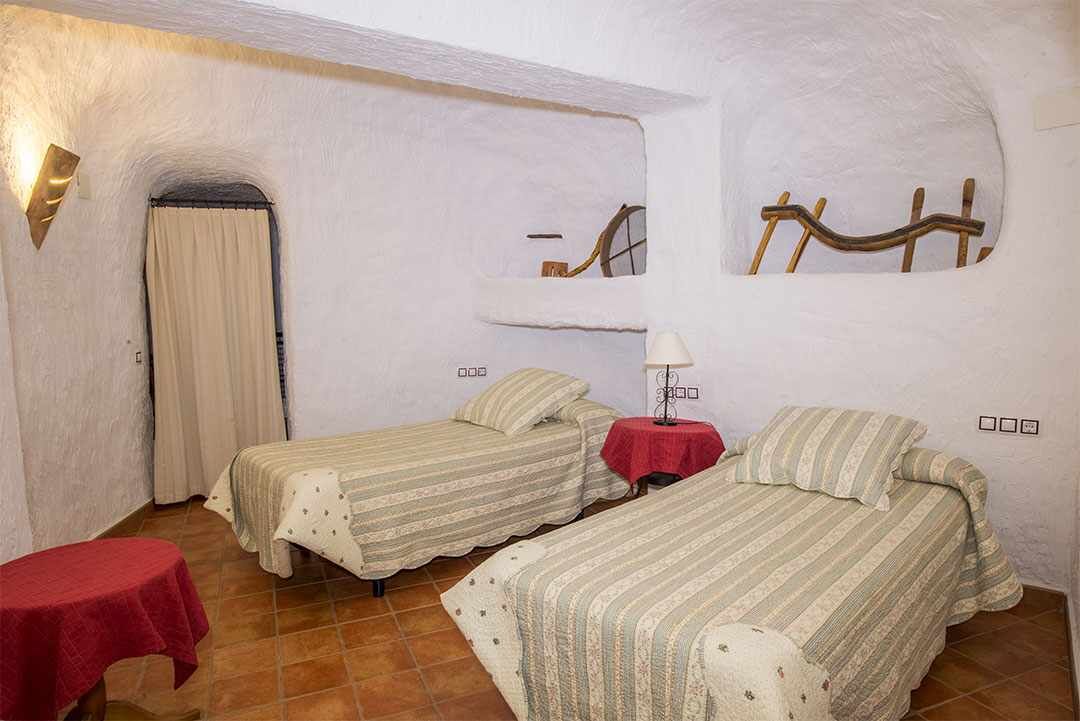 Una habitación con dos camas, una mesita, una lámpara y un espejo en la pared.