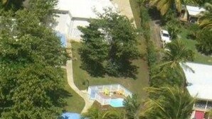 Vue aérienne d’un complexe hôtelier doté d’une piscine, de palmiers et de propriétés situées en bord de mer.