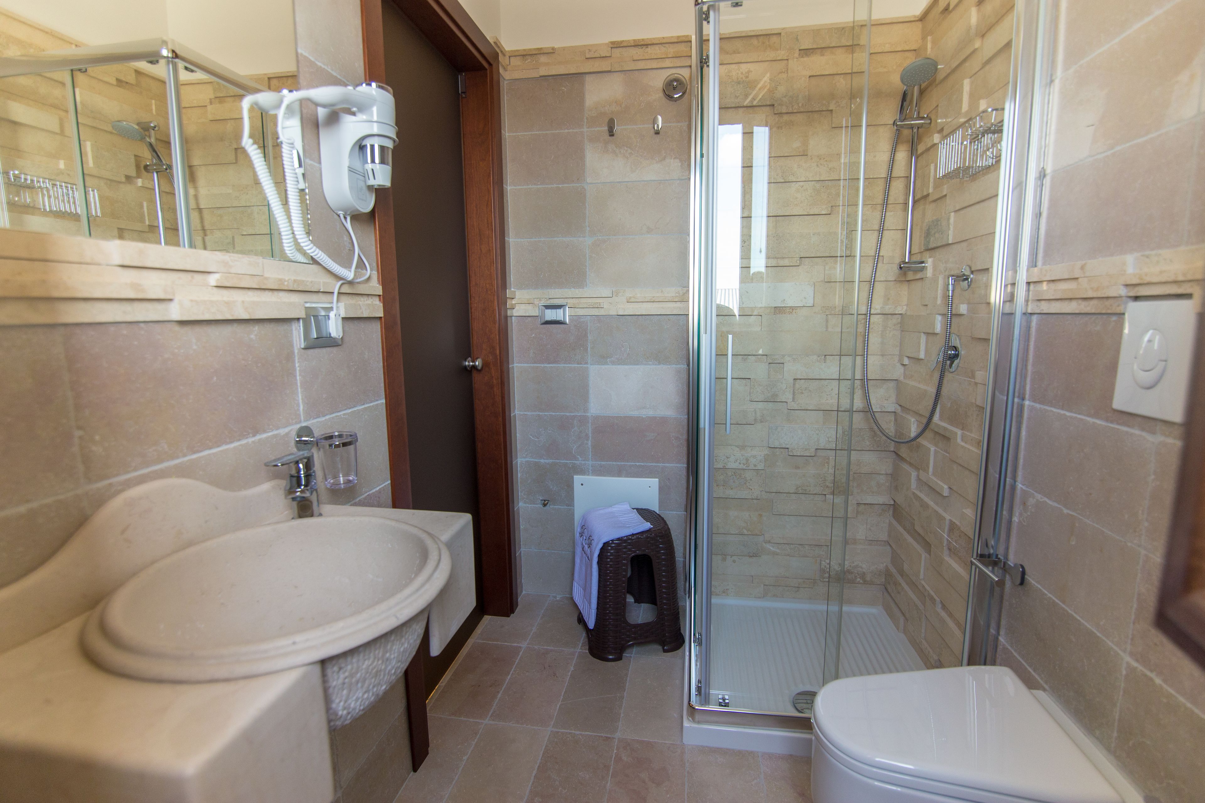 Un baño con lavamanos, inodoro y zona de ducha con mampara de vidrio.