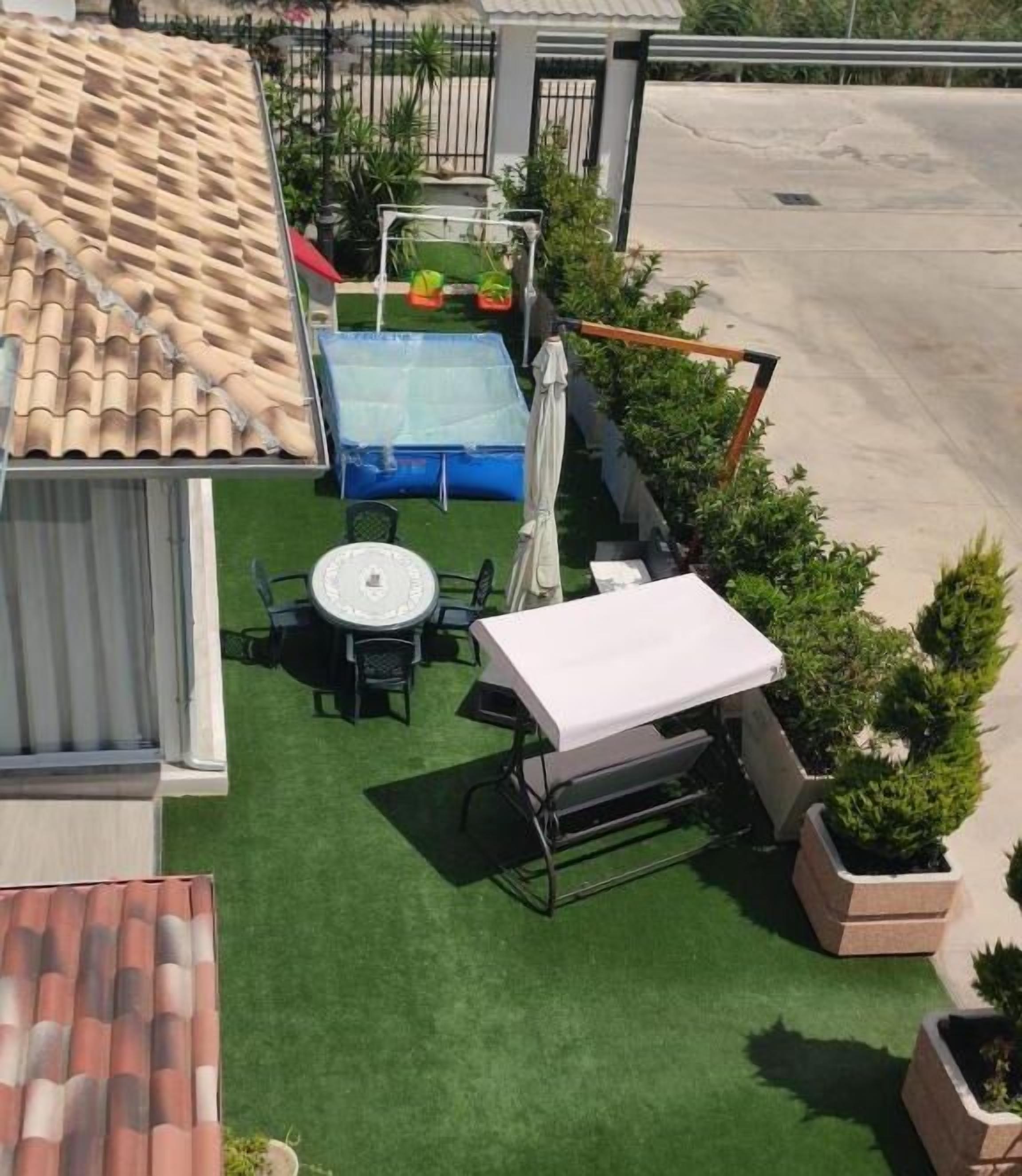A rooftop patio with a swimming pool, a table, and chairs.
