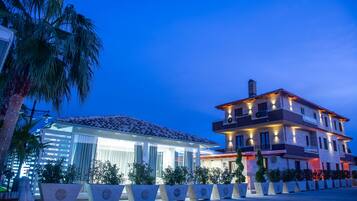 Stunning two-story building with a flat roof and balcony, surrounded by lush greenery and palm trees.