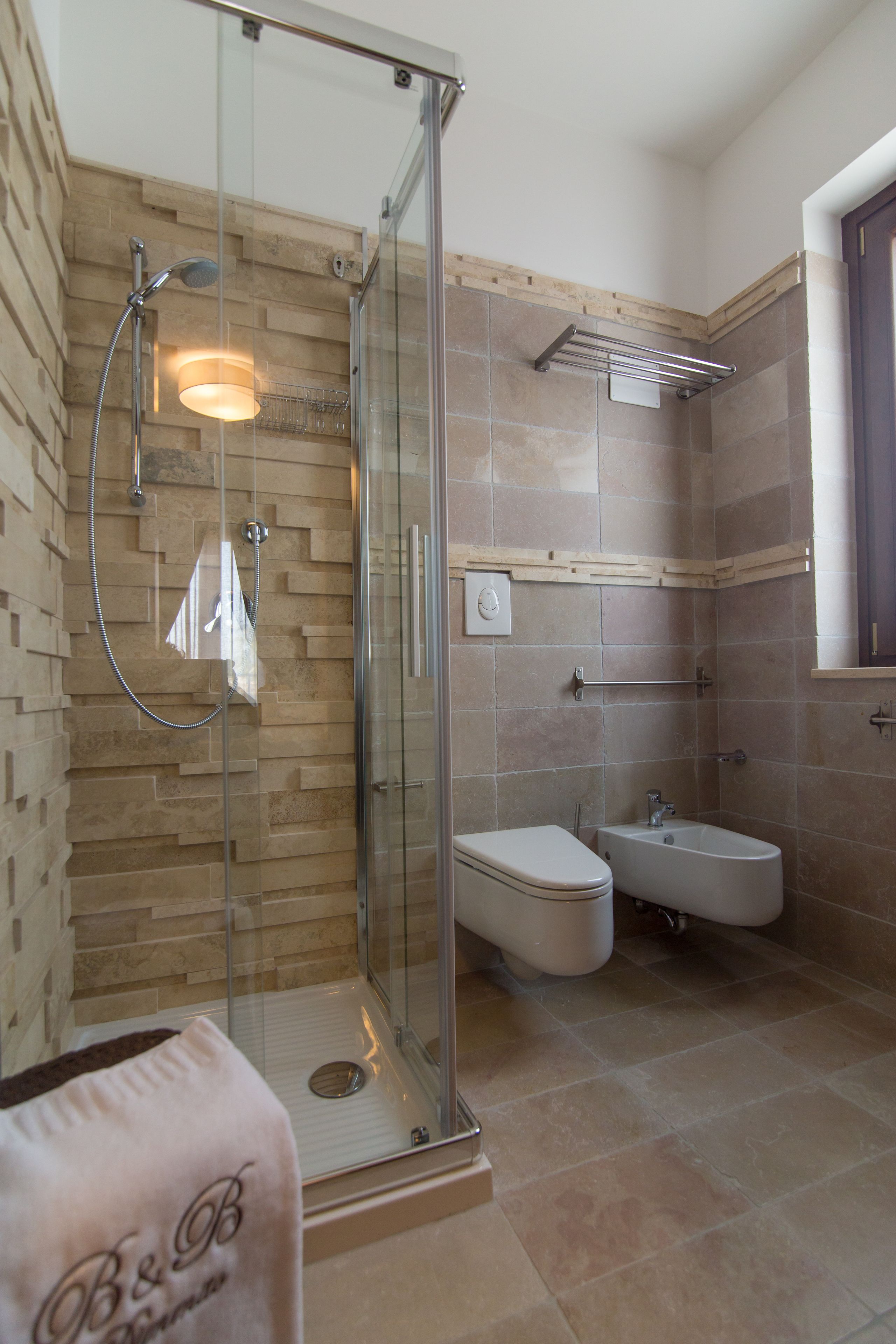 Een moderne badkamer met een glazen douchecabine, een toilet en een hygiëneschuimer.