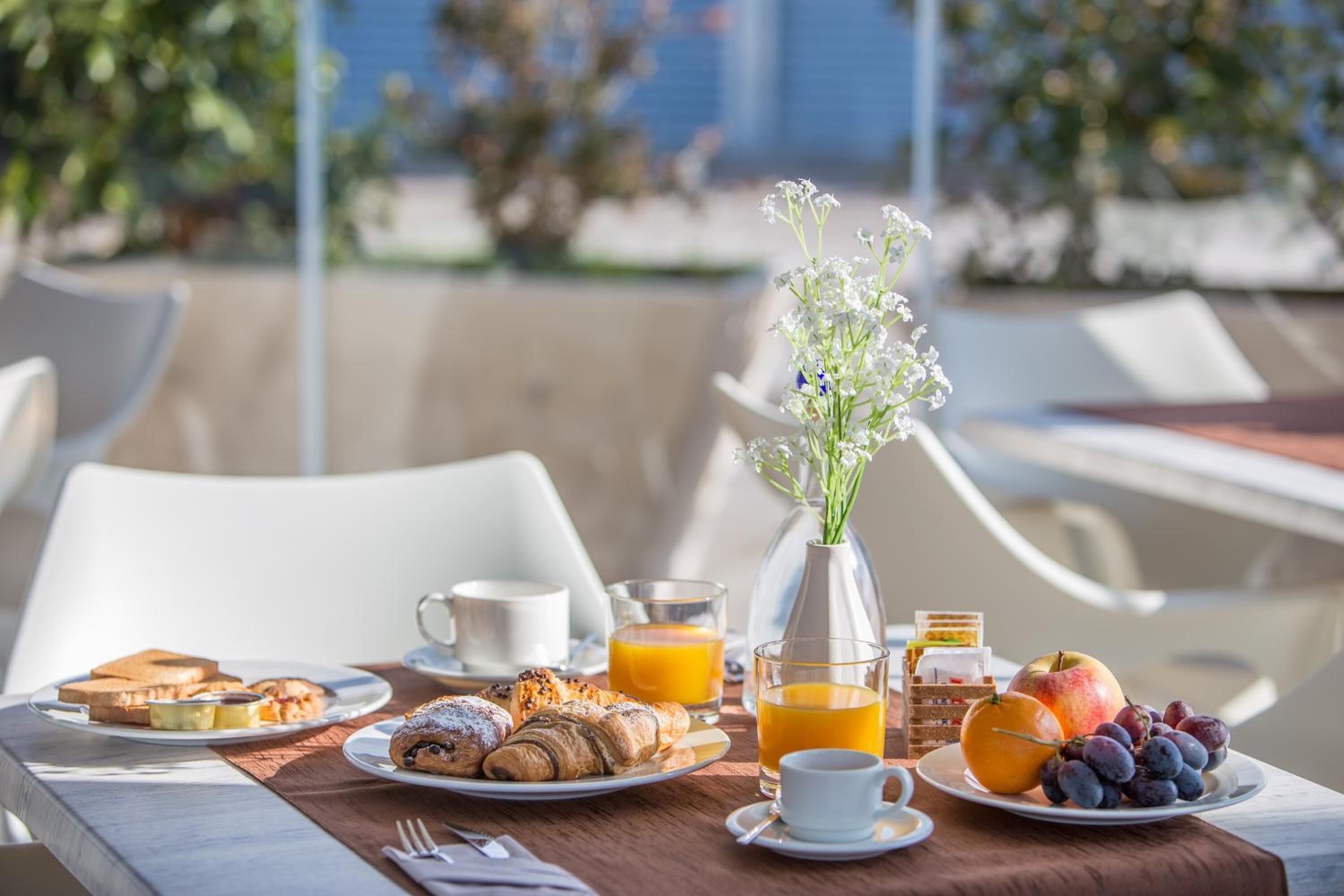 Een ontbijttafel met croissants, brood, fruit en sinaasappelsap.