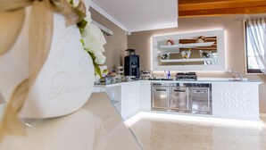 Una cocina moderna con armarios blancos, una cafetera integrada e una isla de vidrio.