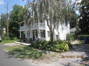 A two-story house with a porch, surrounded by lush greenery and a tree with hanging moss. - Historical Downtown Home (Beaufort)