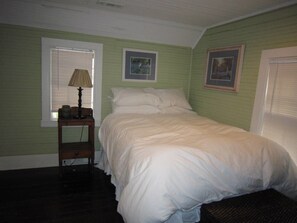 A bedroom with a single bed, a nightstand with a lamp, and two framed pictures on the wall. - Historical Downtown Home (Beaufort)