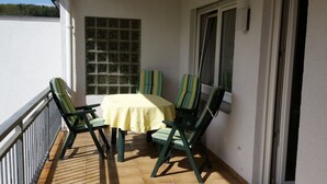 Ein Balkon mit Tisch und Stühlen, ein Fenster und Meerblick.