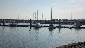 Un port de plaisance où sont amarrés de nombreux bateaux, avec une eau calme et un ciel dégagé.
