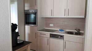 Une cuisine de taille réduite, équipée d’un four encastré, d’un lave-vaisselle et d’un évier.
