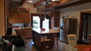 A kitchen with wooden cabinets, a central island, a refrigerator, and a ceiling fan. - 7 Bedroom Manor near Appomattox & Lynchburg (Concord)