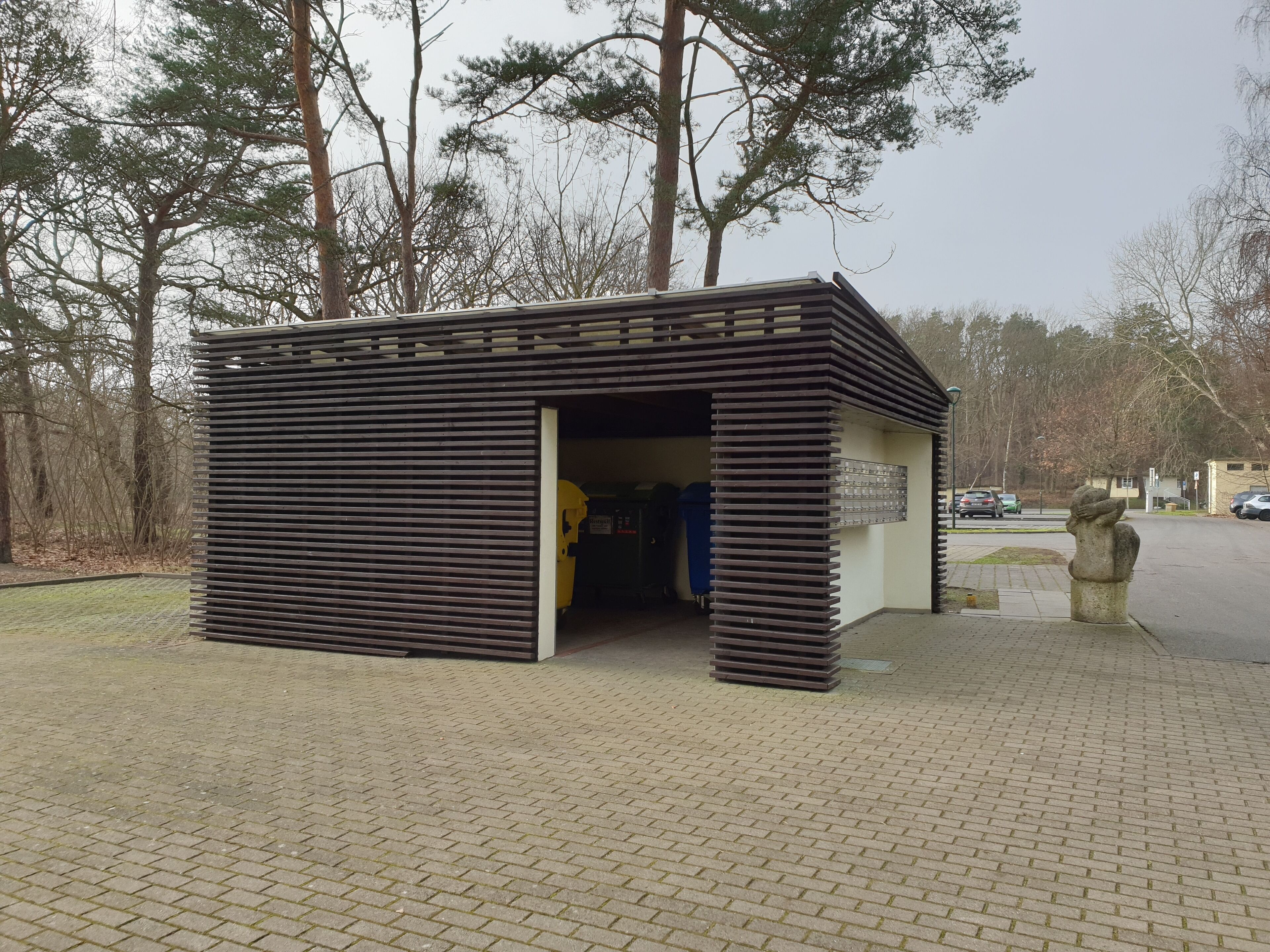 Un pequeño edificio moderno con techo de listones y una puerta de entrada.