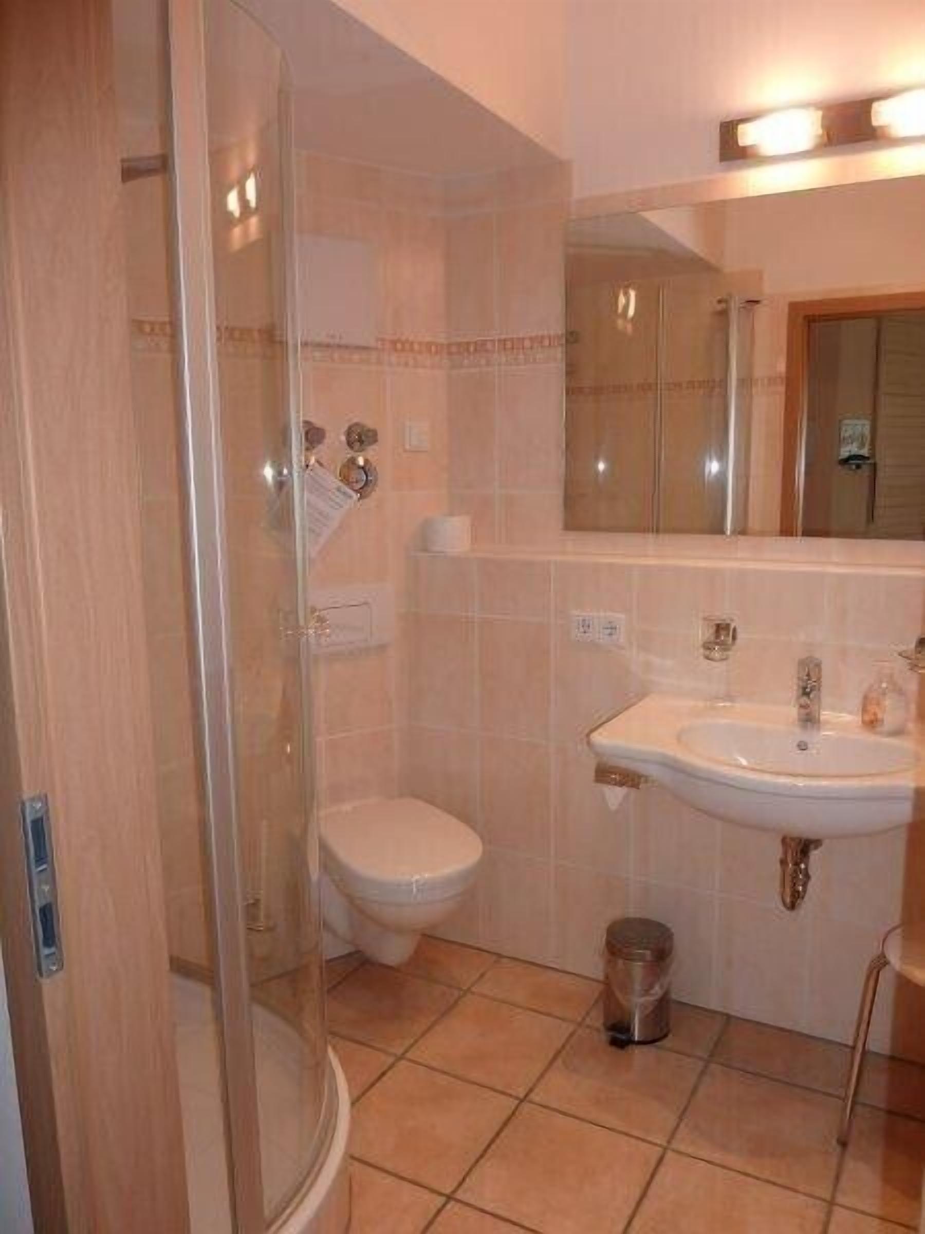 Une salle de bain avec une douche à parois de verre, des toilettes, un lavabo et un miroir au-dessus du lavabo.