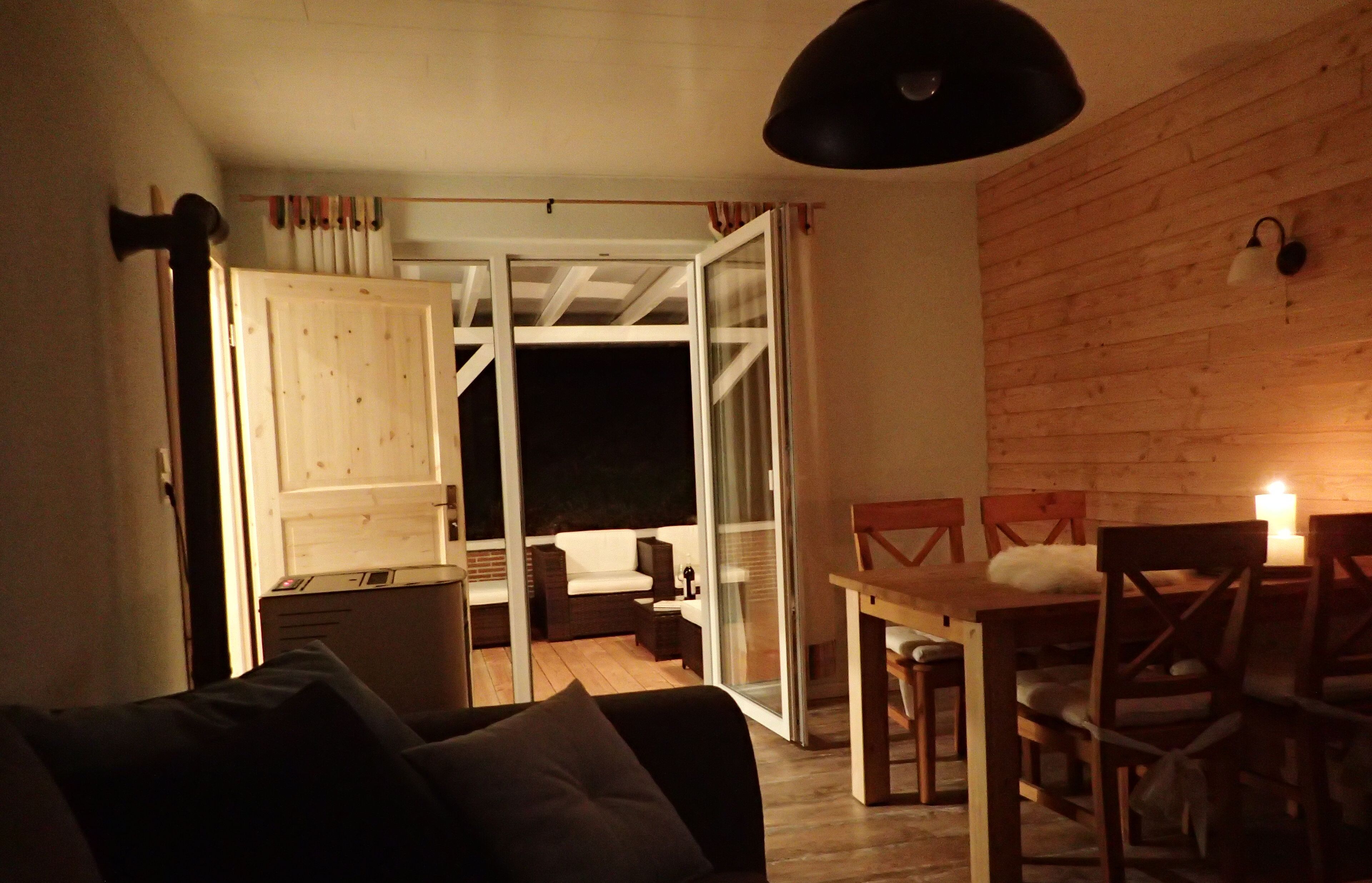 A cozy living area with a sofa, a dining table with chairs, and a sliding glass door leading to an outdoor space.