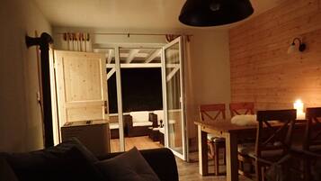 A cozy living area with a sofa, a dining table with chairs, and a sliding glass door leading to an outdoor space.
