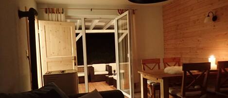 A cozy living area with a sofa, a dining table with chairs, and a sliding glass door leading to an outdoor space.