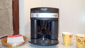 Una cafetera con un panel de control y dos tazas de café sobre una encimera de cocina.