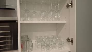 Ein Schrank mit Regalen, auf denen verschiedene Gläser, darunter Weingläser und Bierkrüge, stehen.