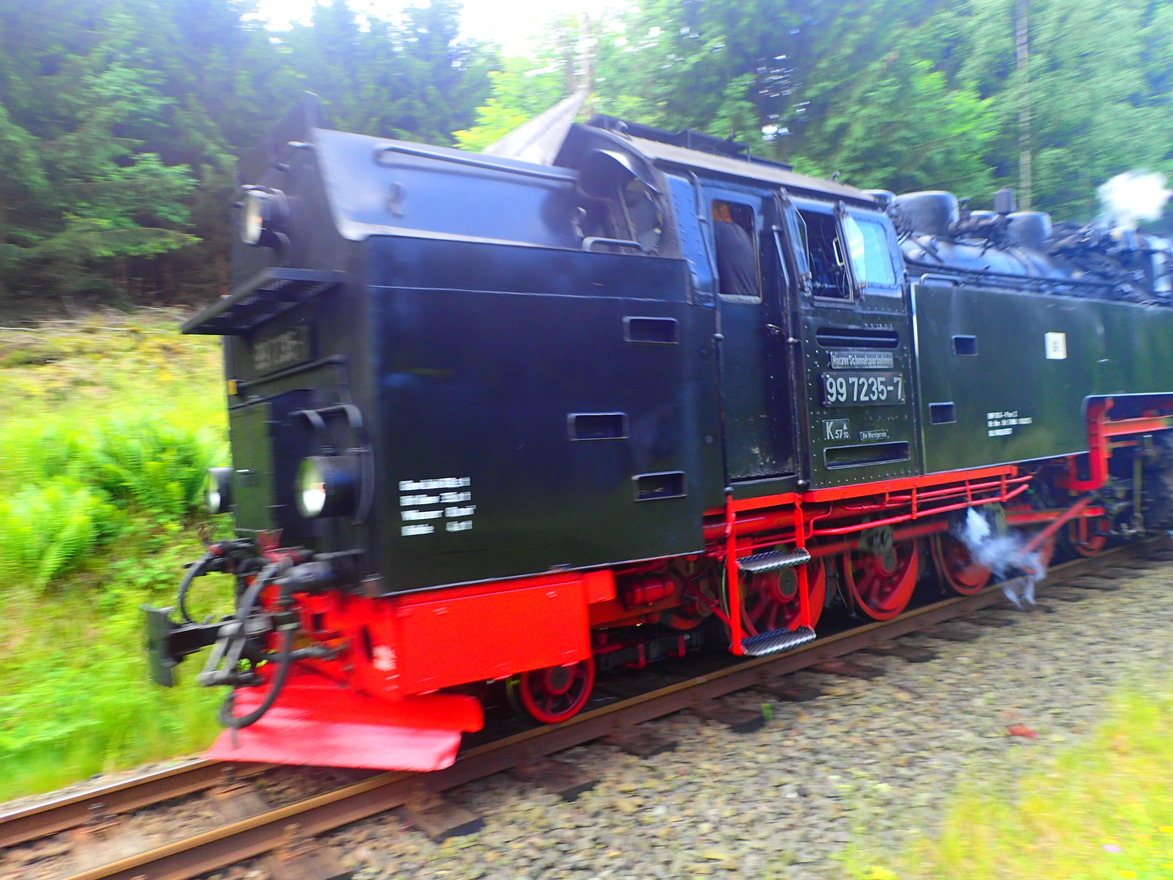 Una locomotora de vapor con ruedas rojas sobre una vía de tren.
