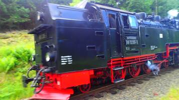 Una locomotora de vapor con ruedas rojas sobre una vía de tren.