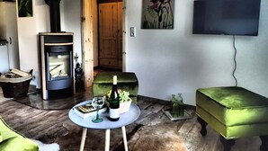 Un salon avec une cheminée, un téléviseur et un canapé vert.