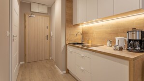Una cocina moderna con armarios de madera, un lavamanos, una cafetera y una encimera con frascos.