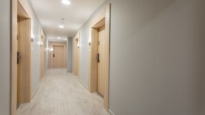 Un pasillo largo y estrecho con puertas de madera a ambos lados, que conduce a habitaciones individuales.