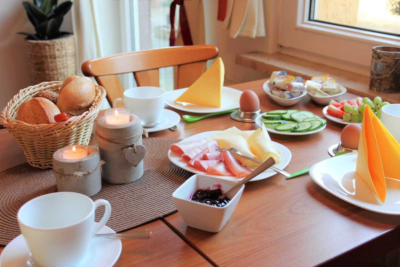 Ein Esstisch mit verschiedenen Speisen, darunter Brot, Käse, Eier und Obst.