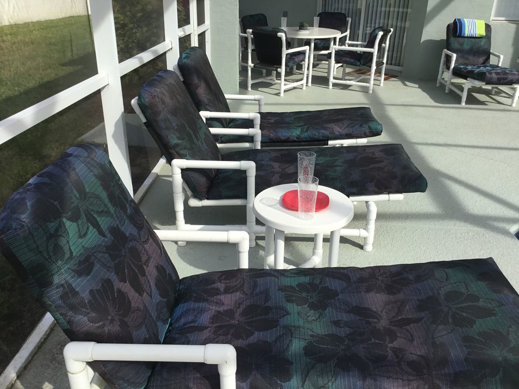 A covered outdoor seating area with lounge chairs and a small table.