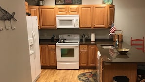 Une cuisine avec des meubles de rangement en bois, un réfrigérateur blanc, une cuisinière et un four à micro-ondes.