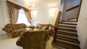 A living room with two patterned sofas, a coffee table, and a wooden staircase. - Cozy house near the gondola in Bansko.  (Bansko)