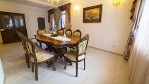 A dining room with a wooden table and chairs, a chandelier, and a painting on the wall. - Cozy house near the gondola in Bansko.  (Bansko)