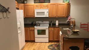 Una cocina con armarios de madera, un refrigerador blanco, una estufa y un microondas.