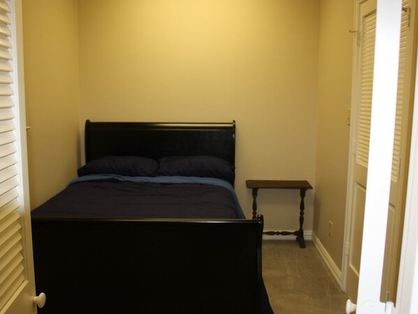 Un dormitorio con cama, mesita de noche y una puerta.