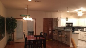 A dining area with a wooden table and chairs, a kitchen with white cabinets and a microwave, and a chandelier hanging from the ceiling. - Family Friendly Lake House Located at Mid-west arm of Lake Fork (Quitman)