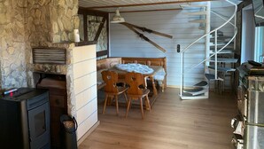 A rustic interior with a stone wall, a wooden dining table with chairs, a fireplace, and a spiral staircase. - Feel-good oasis "Willi" - vacation with dog (Harzgerode)