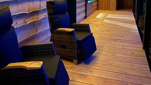 A wooden log cabin interior with a covered wooden deck, wicker chairs, and a wooden floor. - Feel-good oasis "Willi" - vacation with dog (Harzgerode)