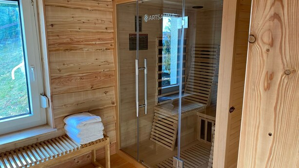 A sauna room with wooden walls, a bench, and a glass door. - Feel-good oasis "Willi" - vacation with dog (Harzgerode)