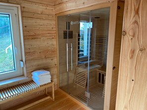 Een sauna met houten wanden, een bank en een glazen deur.