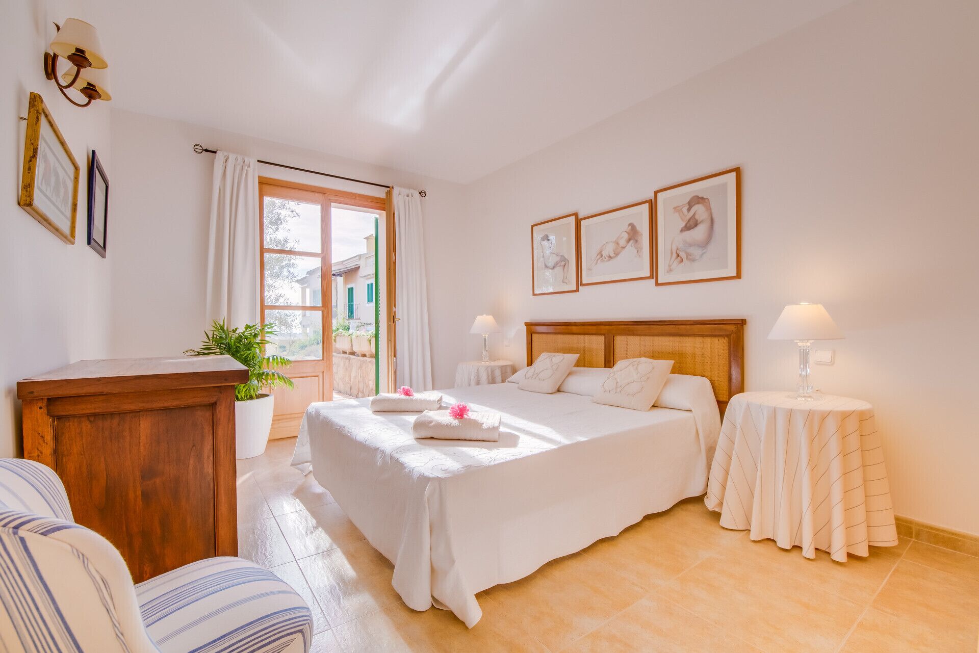 Un dormitorio con una cama grande, dos mesitas de noche, un aparador de madera y una planta en maceta.