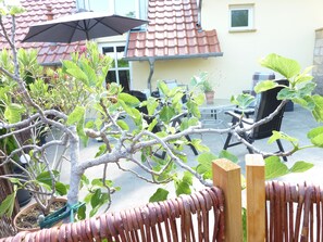 A patio area with a small tree, outdoor furniture, and a potted plant. - Apartment "Stadtoase" in the center of Neustadt an der Weinstrasse (Neustadt an der Weinstraße)