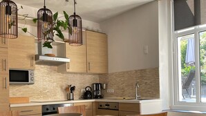 A modern kitchen with wooden cabinets, a built-in microwave, a gas stove, and a large window with a view of the outdoors.
