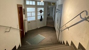 A staircase with handrails, a rug at the bottom, and a door with a wreath on the wall.