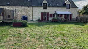 Een stenen boerderij met een ruime tuin, een overdekt terras en een trampoline.